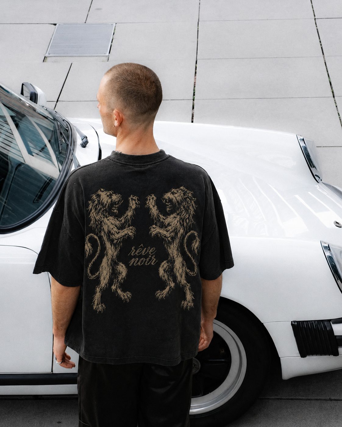 Herald tee — twin lion crest, shot beside a vintage Porsche